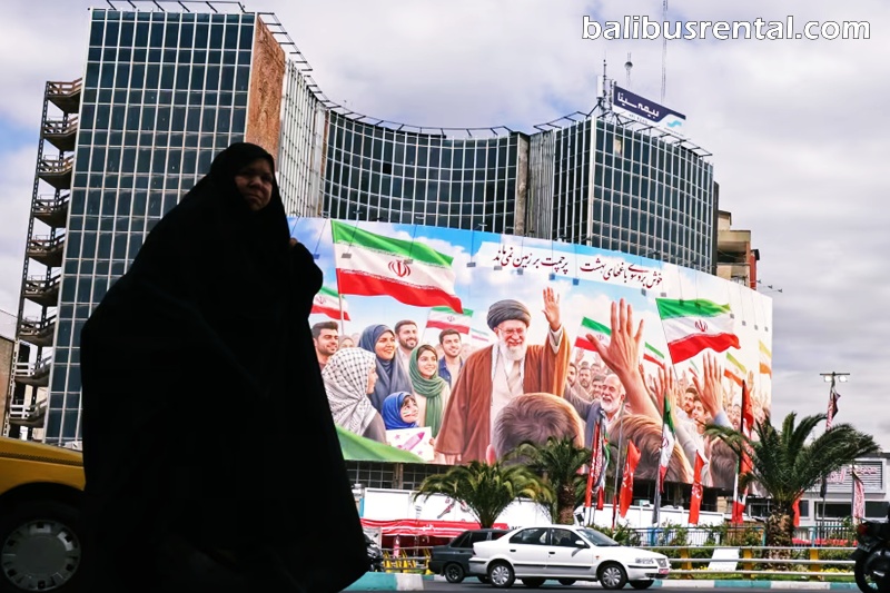 Commuters make their way past a giant billboard of slain Iranian supreme leader Ali Khamenei at the Valiasr Square in Tehran